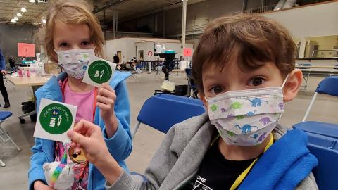 Kids show off their COVID-19 vaccination stickers