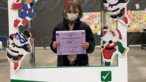 Saige, age 9, holding her COVID-19 Vaccine Superstar certificate in Regina.