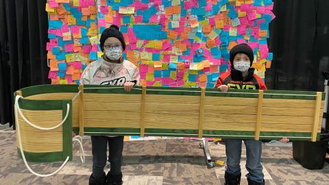 Two children hold a handmade toboggan they won at the Prairieland Park vaccine clinic in Saskatoon.