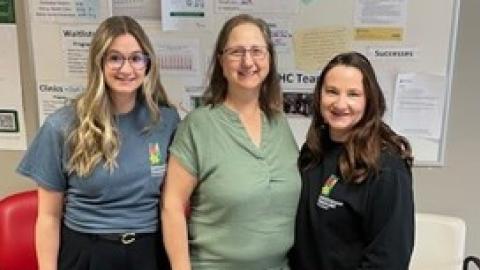 Three health-care professionals standing together in front of a white board that reads “Kidney Health Centre”