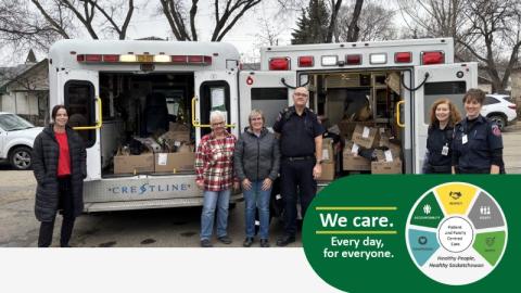 Members of Emergency Services and community standing in front of two ambulances. Both are full of packed food for a food drive.