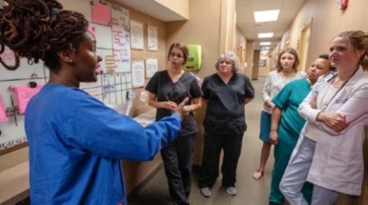 Image of staff huddling at a VM board